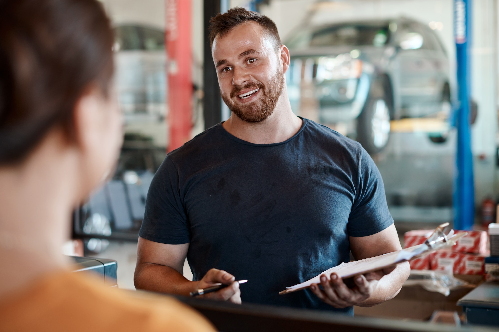 Shot of a woman talking to a mechanic in an auto repair shop