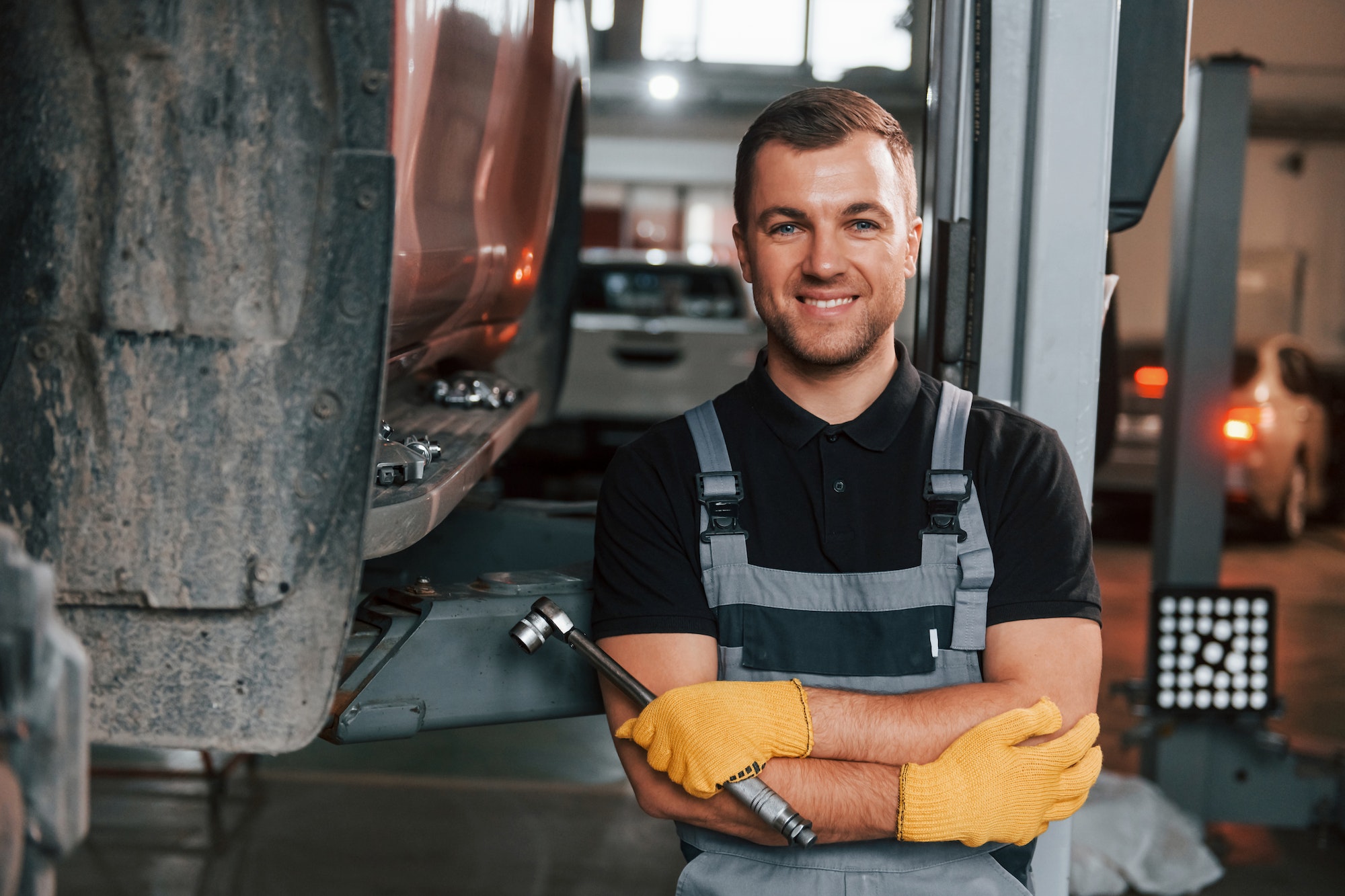 Standing with arms crossed. Man in uniform is working in the auto service